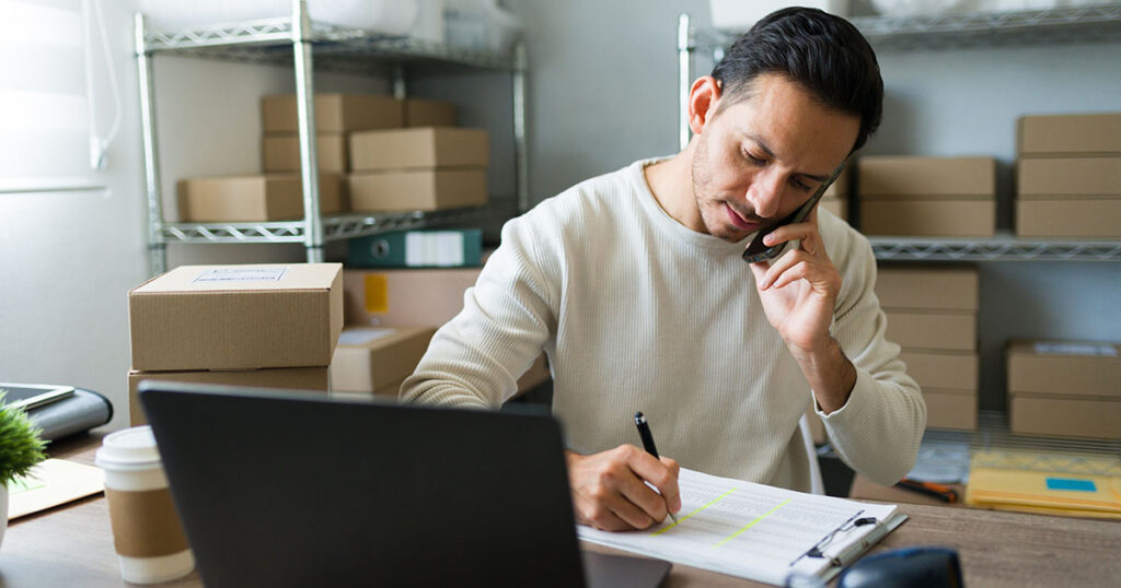 Latin entrepreneur taking notes while talking on the phone