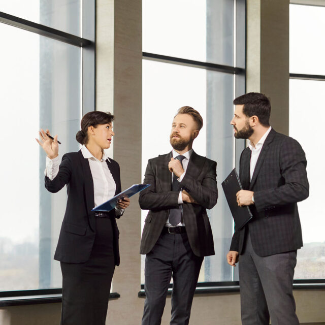 Confident realtor presenting commercial property to potential investors in office building. Professional business people discussing opportunities, analyzing investment potential and location benefits.